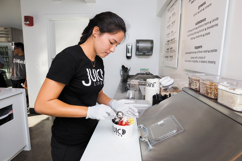 Alexandra Friedlich making an Acai Bowl behind the counter at Juic'd Life in Kakaako 