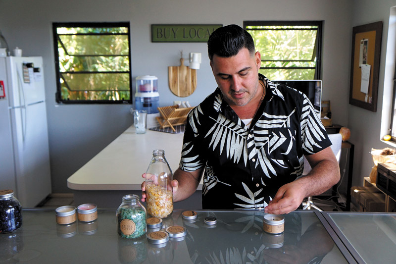 Aloha Elixir founder Keoki Tavares adds gemstones to a candle  